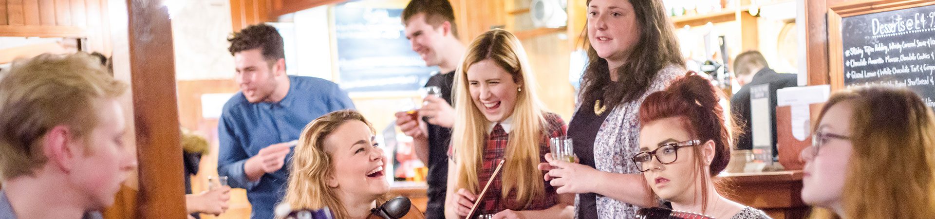 Oileanaich aig seisean ciùil - Students at a local music session